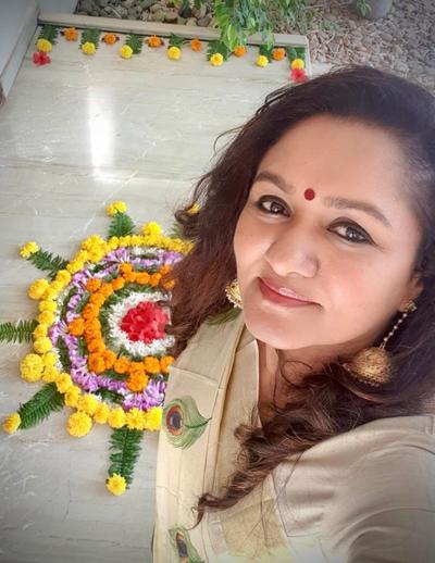 A malayali woman celebrates onam with a floral carpet at the threshold of her house. Image: sumitha suseelan.